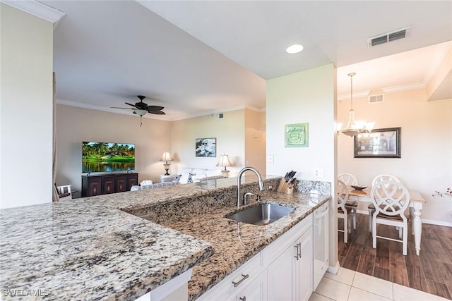 kitchen with visible vents, a sink, white cabinetry, and light stone counters