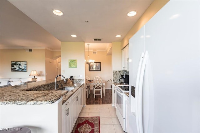 kitchen featuring light tile patterned flooring, a sink, white appliances, a peninsula, and visible vents
