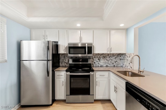 1004 Manatee Rd Unit H201, Naples, FL 34114 - kitchen with stainless steel appliances, a raised ceiling, ornamental molding, white cabinets, and tasteful backsplash