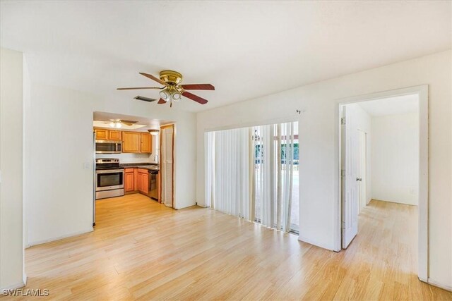 unfurnished living room with a sink, a ceiling fan, visible vents, and light wood-style flooring