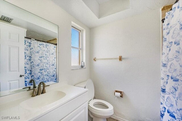 bathroom featuring toilet, curtained shower, and vanity
