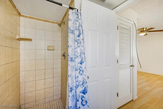 full bathroom with wood finished floors, a tile shower, and a ceiling fan