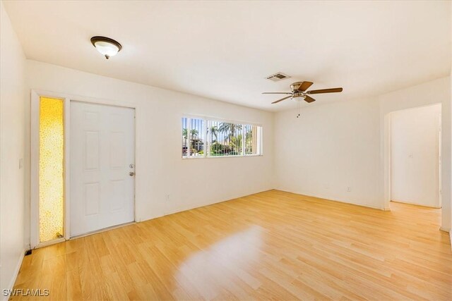 unfurnished room with a ceiling fan, visible vents, and light wood-type flooring