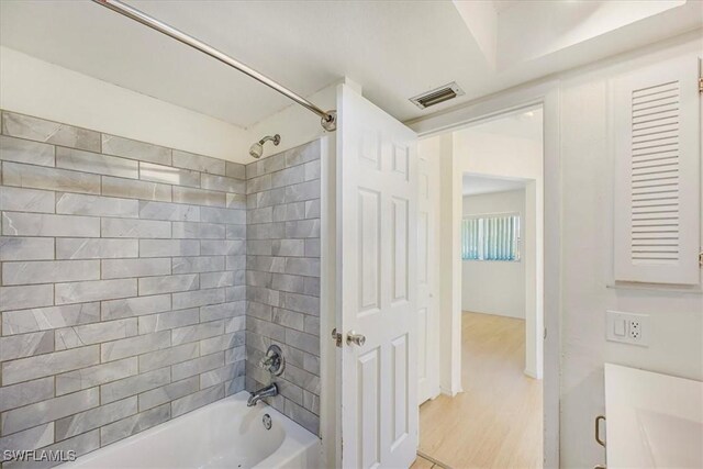 full bathroom with visible vents, bathing tub / shower combination, and wood finished floors