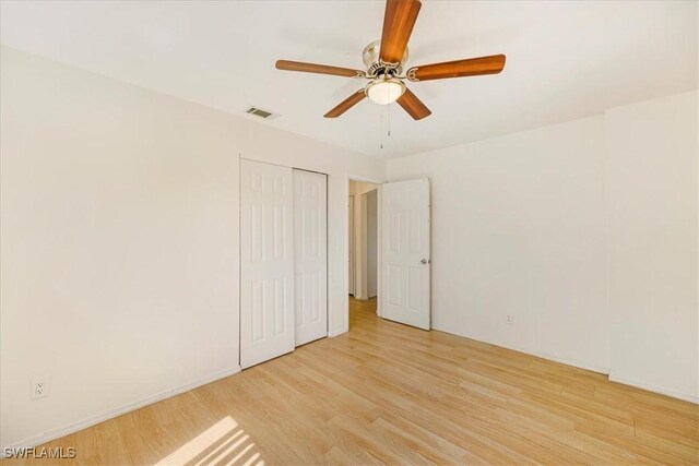 unfurnished bedroom featuring visible vents, light wood finished floors, and a closet
