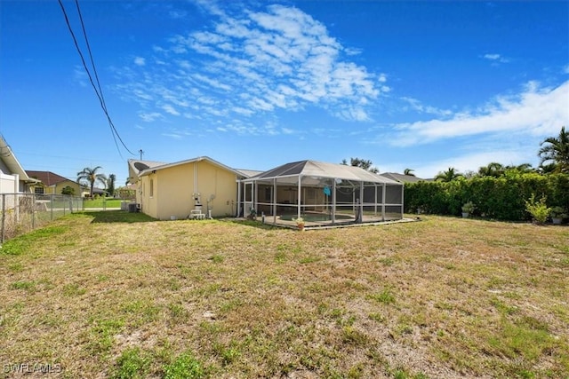 rear view of house with a lanai, a yard, and fence