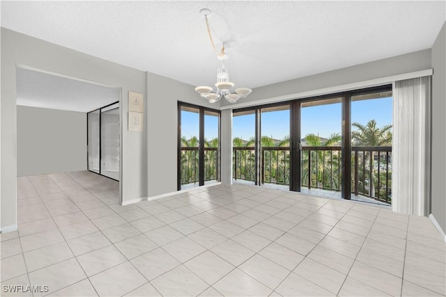 845 Collier Ct Unit 503, Marco Island, FL 34145 - unfurnished room featuring a chandelier, healthy amount of natural light, baseboards, a textured ceiling, and light tile patterned flooring