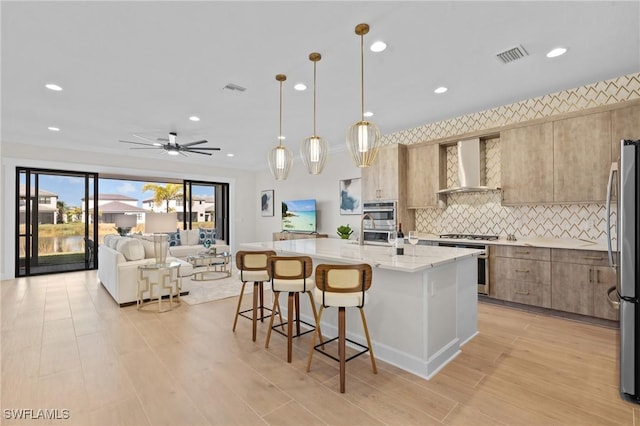20333 Fair Oak Ln, Estero, FL 33928 - kitchen with visible vents, a kitchen bar, open floor plan, wall chimney range hood, and backsplash