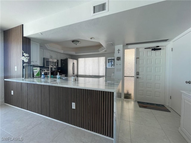6672 Estero Blvd Unit A606, Fort Myers Beach, FL 33931 - kitchen with stainless steel appliances, a tray ceiling, a peninsula, light countertops, and light tile patterned floors