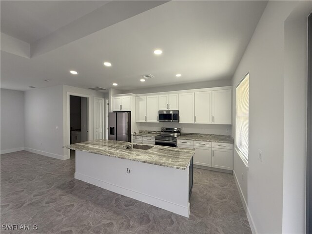 2803 17th St W, Lehigh Acres, FL 33971 - kitchen featuring white cabinetry, a center island with sink, a sink, and stainless steel appliances