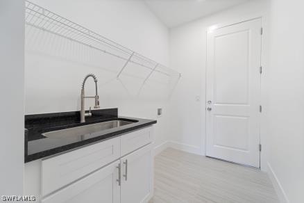 2803 17th St W, Lehigh Acres, FL 33971 - washroom with baseboards, light wood-style floors, cabinet space, and a sink