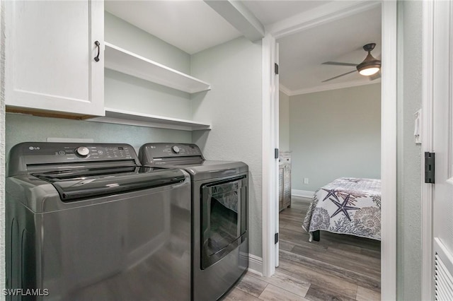 laundry room with ornamental molding, independent washer and dryer, cabinet space, ceiling fan, and wood finished floors