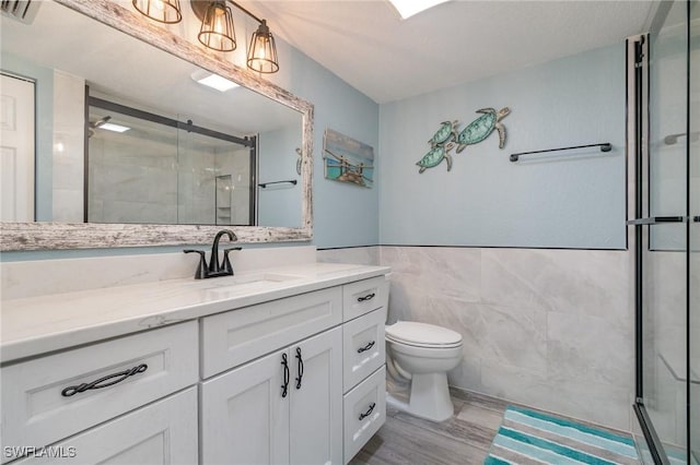 full bathroom featuring vanity, visible vents, toilet, tile walls, and a stall shower