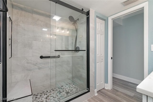 full bath with visible vents, baseboards, a stall shower, and wood finished floors