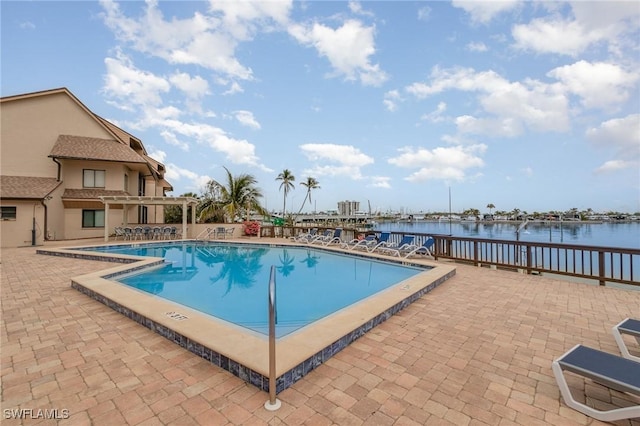 pool featuring a water view, a patio, and a pergola