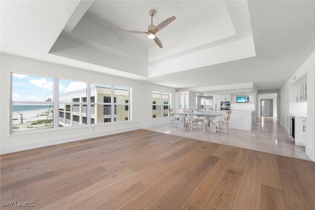 3127 W Gulf Dr Unit 106, Sanibel, FL 33957 - unfurnished living room with a tray ceiling, light wood-style flooring, ceiling fan, and a healthy amount of sunlight