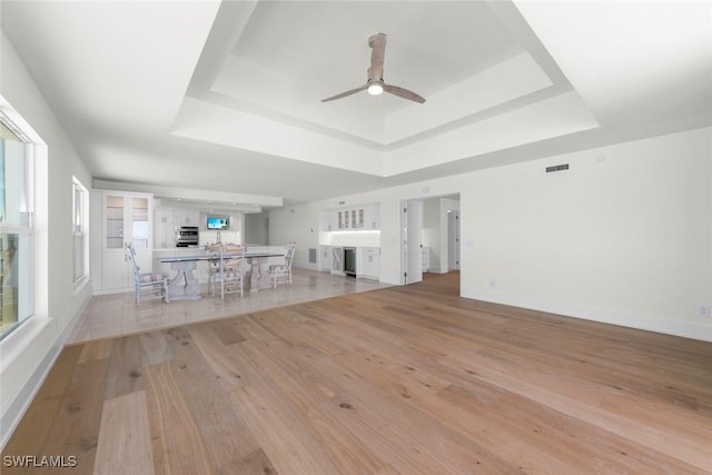 3127 W Gulf Dr Unit 106, Sanibel, FL 33957 - unfurnished living room with a tray ceiling, baseboards, light wood finished floors, visible vents, and a ceiling fan