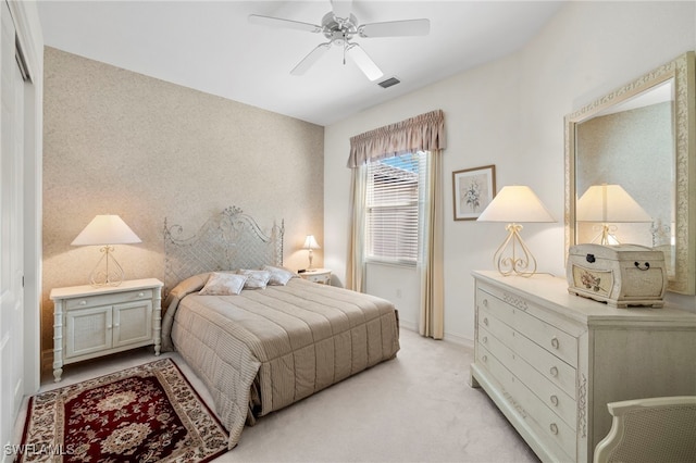 bedroom featuring light carpet, a ceiling fan, visible vents, and baseboards