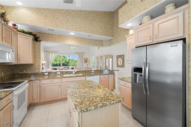 kitchen featuring a peninsula, light brown cabinetry, a sink, light tile patterned flooring, and white appliances