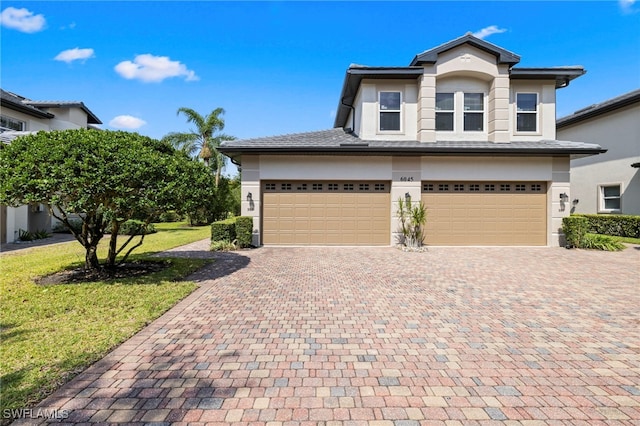 view of front of home featuring stucco siding, a front lawn, decorative driveway, and a garage
