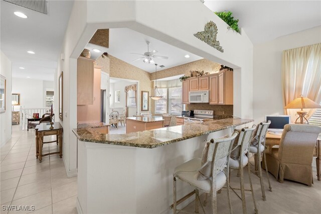 kitchen with visible vents, a ceiling fan, white microwave, a peninsula, and electric range