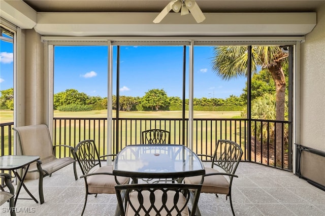 sunroom with a ceiling fan, outdoor dining space, and golf course view