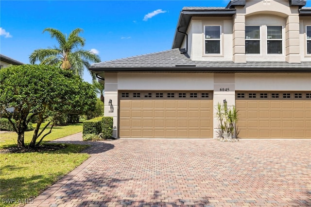 view of front facade with stucco siding, a front lawn, and decorative driveway