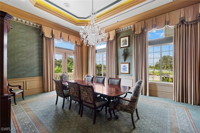 carpeted dining area with a wainscoted wall, ornamental molding, french doors, a decorative wall, and a chandelier