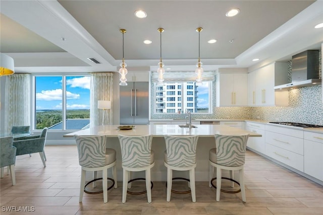 4971 Bonita Bay Blvd Unit 606, Bonita Springs, FL 34134 - kitchen with an island with sink, a raised ceiling, built in refrigerator, gas stovetop, and wall chimney range hood