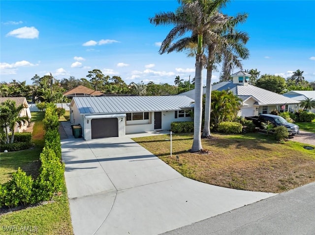 single story home with a standing seam roof, a garage, metal roof, a front lawn, and concrete driveway