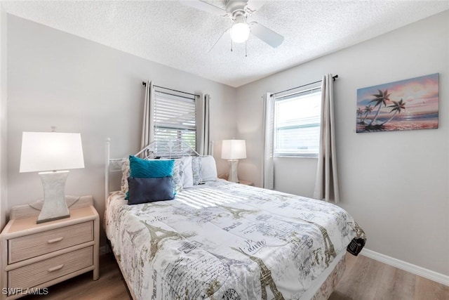 bedroom with ceiling fan, a textured ceiling, baseboards, and wood finished floors