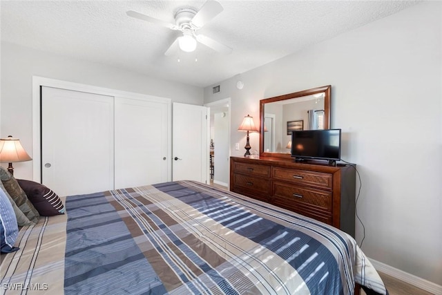 bedroom featuring a closet, visible vents, a textured ceiling, and baseboards