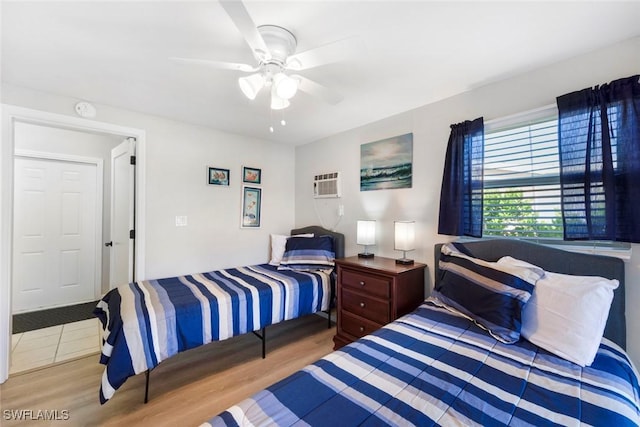 bedroom featuring a ceiling fan, wood finished floors, and a wall mounted air conditioner