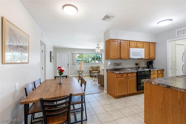 kitchen with visible vents, white microwave, dark countertops, and black range with electric stovetop