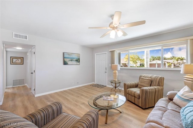 living room featuring light wood-type flooring, ceiling fan, baseboards, and visible vents