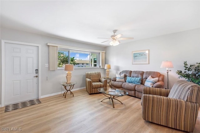 living room featuring light wood-style flooring, baseboards, and a ceiling fan