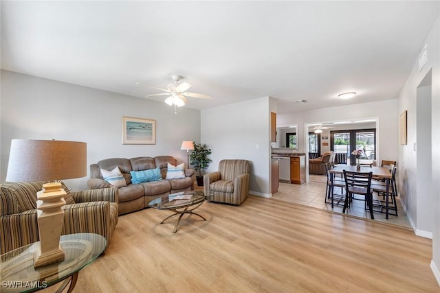 living area featuring light wood-type flooring, ceiling fan, and baseboards