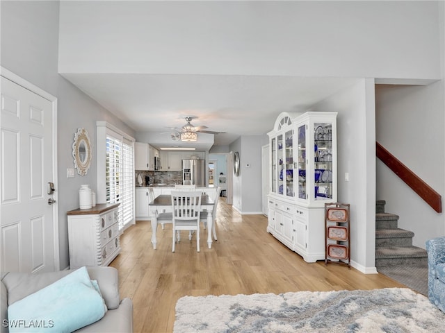 21687/689 Indian Bayou Dr, Fort Myers Beach, FL 33931 - dining area featuring a ceiling fan, light wood-style flooring, baseboards, and stairs