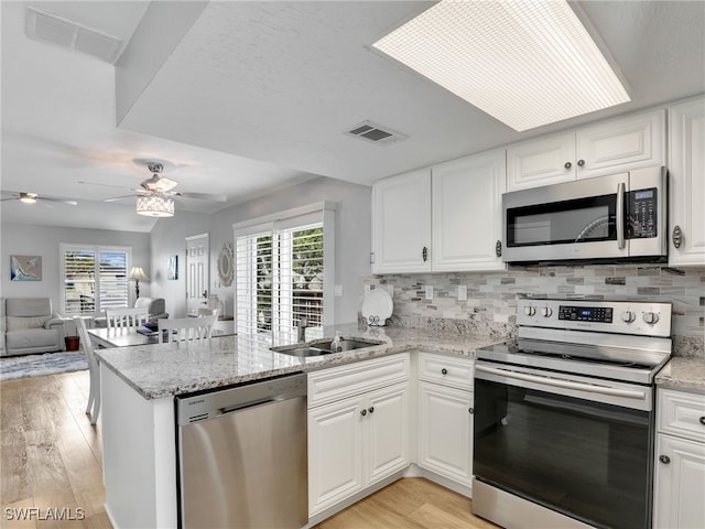 21687/689 Indian Bayou Dr, Fort Myers Beach, FL 33931 - kitchen with stainless steel appliances, a peninsula, light wood-style floors, open floor plan, and healthy amount of natural light
