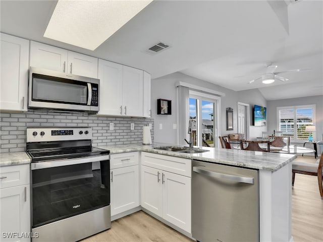 21687/689 Indian Bayou Dr, Fort Myers Beach, FL 33931 - kitchen featuring appliances with stainless steel finishes, a peninsula, a sink, light wood-style flooring, and decorative backsplash