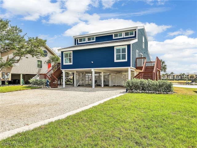 21687/689 Indian Bayou Dr, Fort Myers Beach, FL 33931 - coastal home with a carport, stairway, driveway, and a front lawn