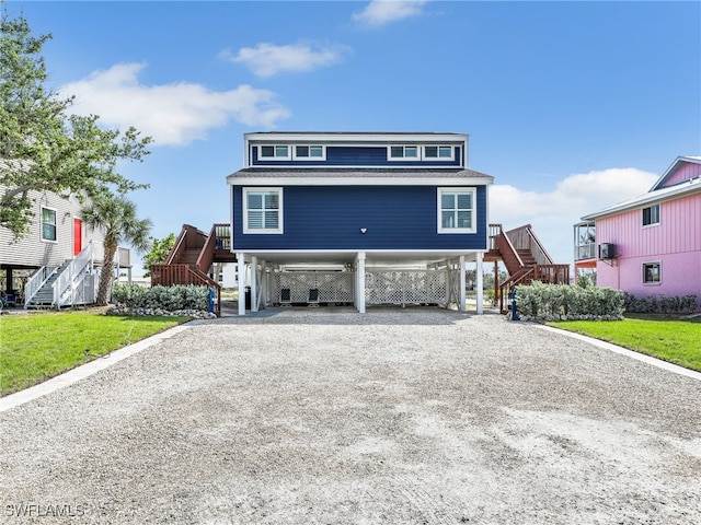 21687/689 Indian Bayou Dr, Fort Myers Beach, FL 33931 - raised beach house featuring stairs, gravel driveway, a carport, and a shingled roof