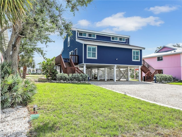 21687/689 Indian Bayou Dr, Fort Myers Beach, FL 33931 - coastal home with stairway, a carport, driveway, and a front lawn