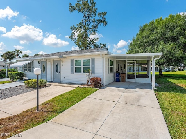 ranch-style house with concrete driveway, an attached carport, and a front lawn