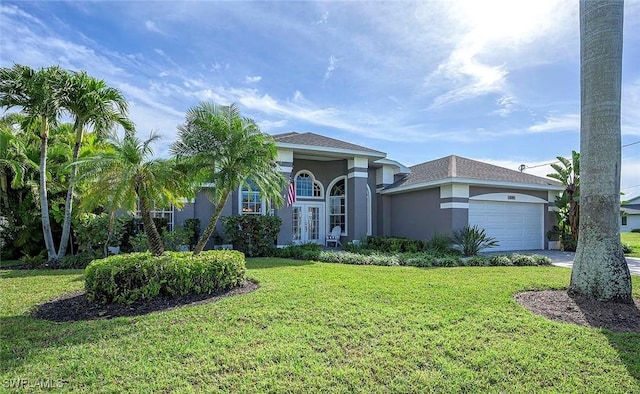 view of front of property featuring driveway, a garage, a front yard, stucco siding, and french doors