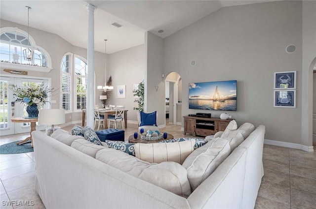 living room featuring arched walkways, high vaulted ceiling, baseboards, and visible vents