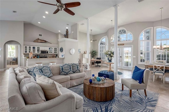 living area with decorative columns, high vaulted ceiling, and ceiling fan with notable chandelier