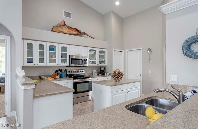 kitchen featuring a sink, stainless steel appliances, light tile patterned floors, visible vents, and white cabinets