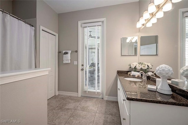 bathroom with baseboards, tile patterned flooring, and vanity