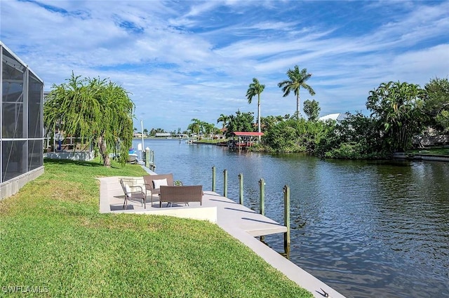 dock area with a lanai, a water view, a patio area, and a yard